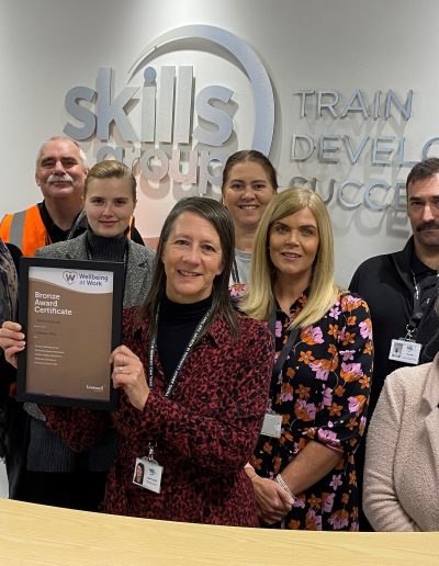 team of individuals holding their bronze award in front of skills logo