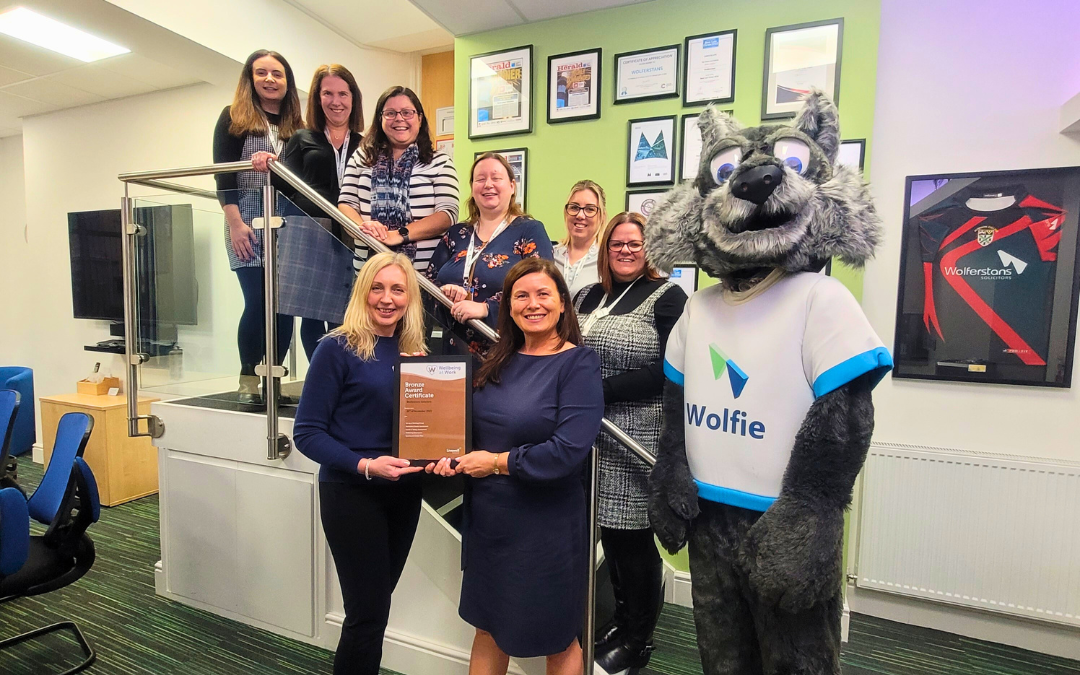 Group of individuals smiling with their award for wolferstans with their mascot Wolfie