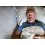 Male sleeping in bed with a blue shirt on.